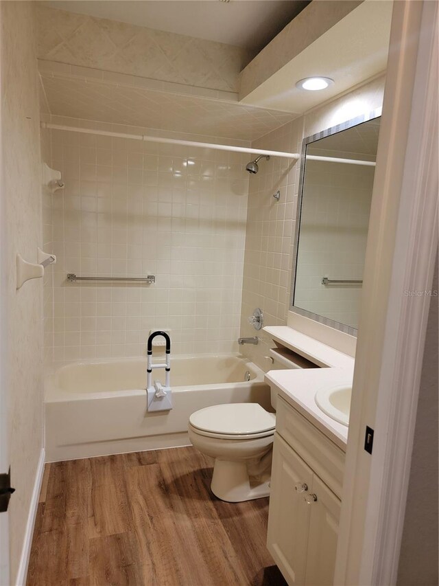 full bathroom with hardwood / wood-style floors, vanity, toilet, and tiled shower / bath