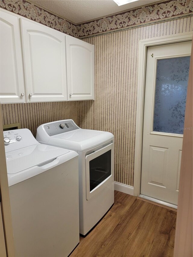 laundry room featuring hardwood / wood-style floors, cabinets, and independent washer and dryer