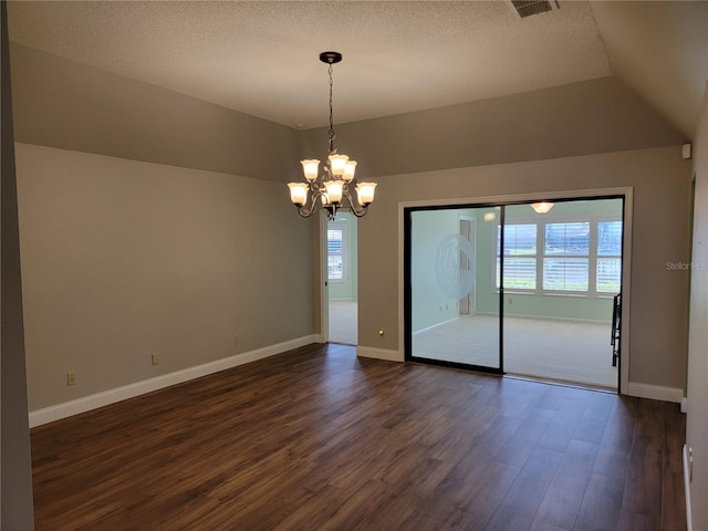 empty room with a textured ceiling, lofted ceiling, a chandelier, and dark hardwood / wood-style floors