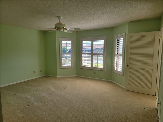 carpeted spare room featuring ceiling fan and a textured ceiling