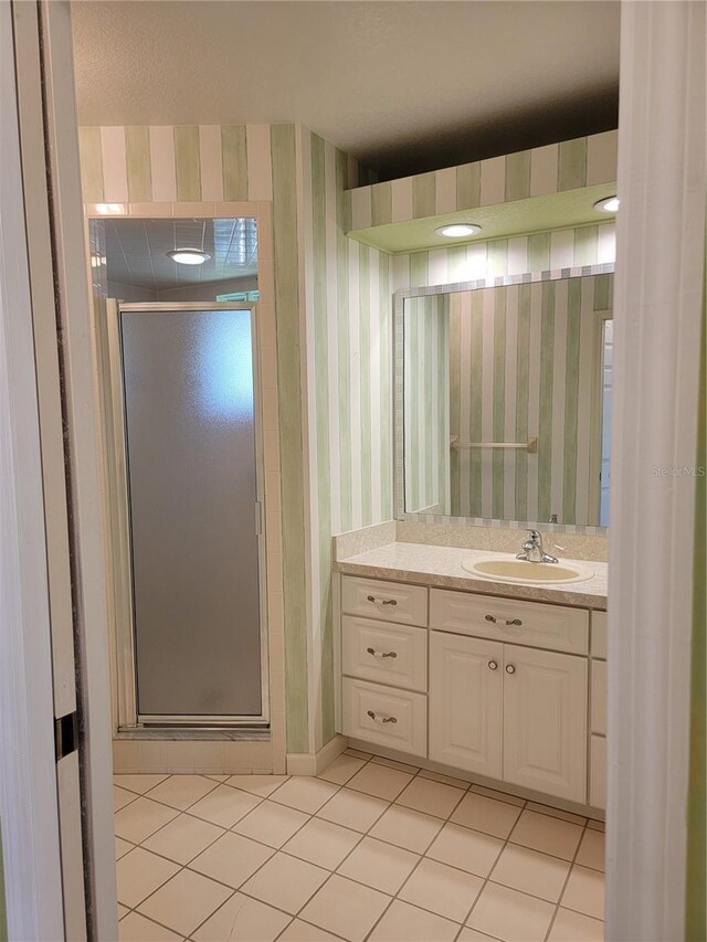 bathroom with tile patterned flooring, vanity, and a shower with door