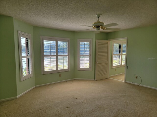 spare room featuring ceiling fan, light colored carpet, and a wealth of natural light