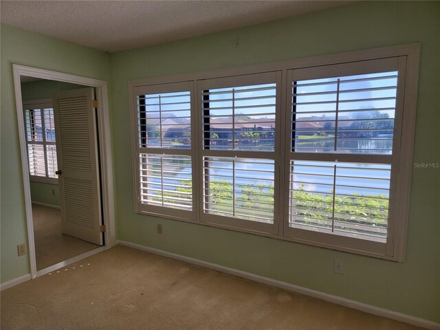 carpeted empty room with a textured ceiling