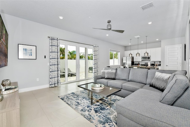 tiled living room with ceiling fan and french doors