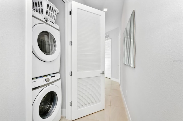 laundry area with light tile patterned flooring and stacked washer and dryer