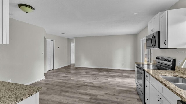 kitchen featuring light wood-type flooring, white cabinets, stainless steel appliances, and stone countertops