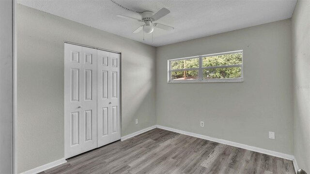 unfurnished bedroom with ceiling fan, a closet, and wood-type flooring