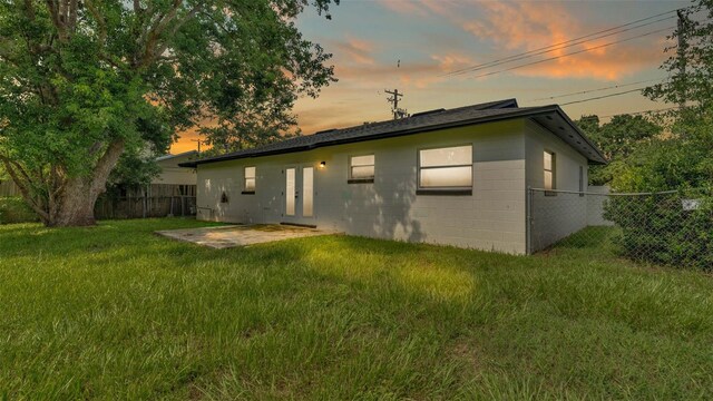 back house at dusk with a lawn