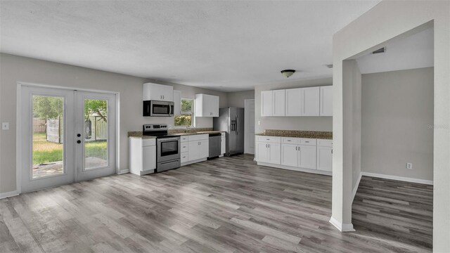 kitchen with french doors, appliances with stainless steel finishes, white cabinetry, light hardwood / wood-style flooring, and sink