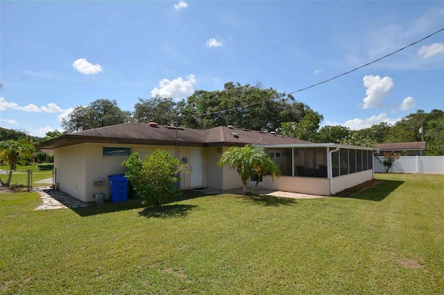 rear view of property featuring a sunroom and a yard