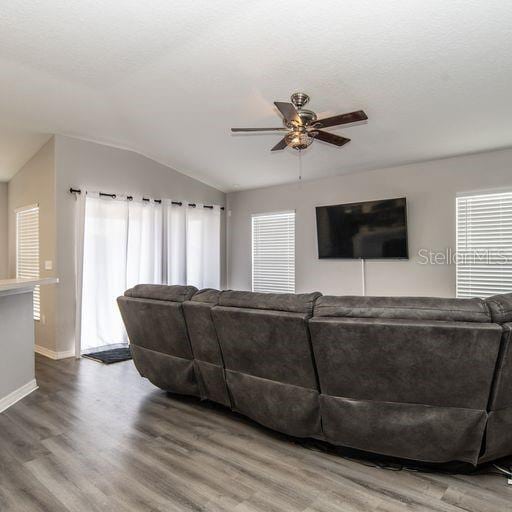 living room with ceiling fan, hardwood / wood-style floors, and lofted ceiling