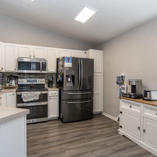 kitchen featuring white cabinets, backsplash, and stainless steel appliances