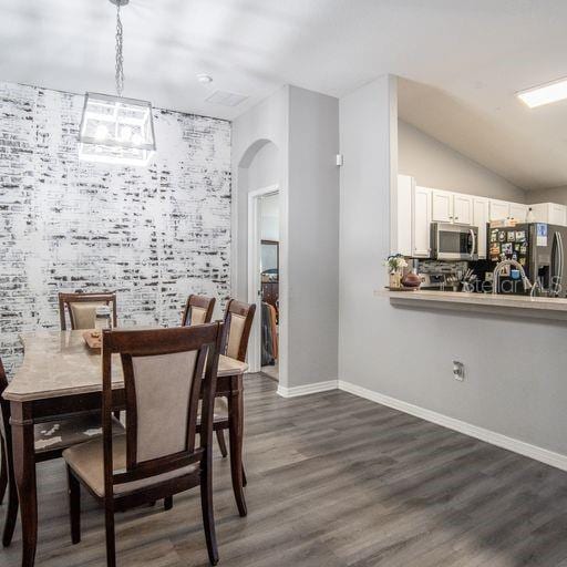 dining space with vaulted ceiling and dark wood-type flooring