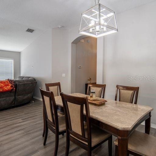 dining area with hardwood / wood-style flooring and an inviting chandelier