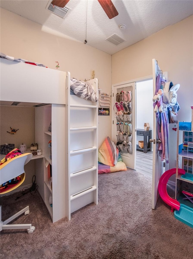 carpeted bedroom with ceiling fan and a textured ceiling