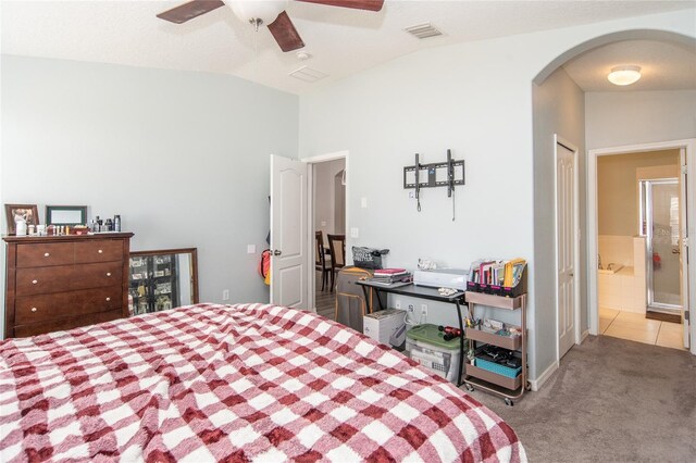 bedroom with ceiling fan, lofted ceiling, light carpet, and connected bathroom