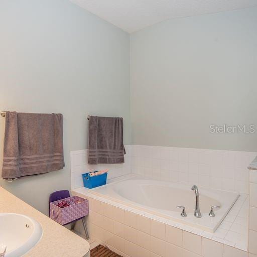 bathroom with vanity and a relaxing tiled tub