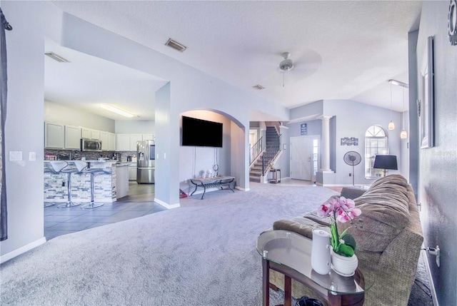 living room with decorative columns, light carpet, ceiling fan, and a textured ceiling