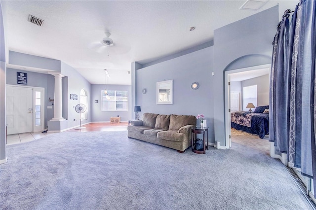 carpeted living room featuring a textured ceiling, vaulted ceiling, decorative columns, and ceiling fan