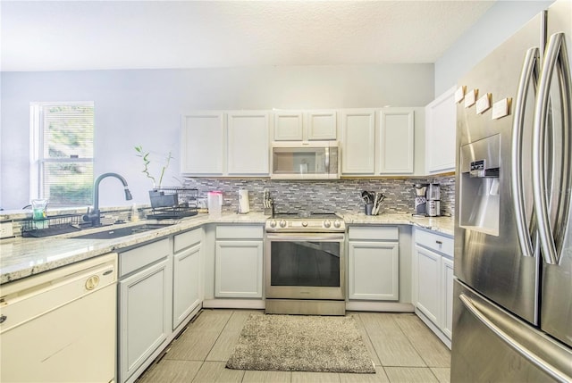 kitchen featuring tasteful backsplash, stainless steel appliances, sink, light stone countertops, and light tile patterned floors