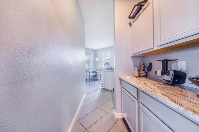 kitchen with white cabinetry, light stone countertops, and light tile patterned floors