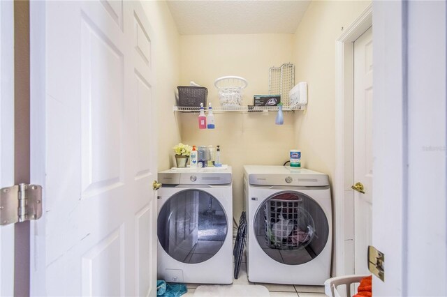 laundry area with washer and dryer and light tile patterned floors