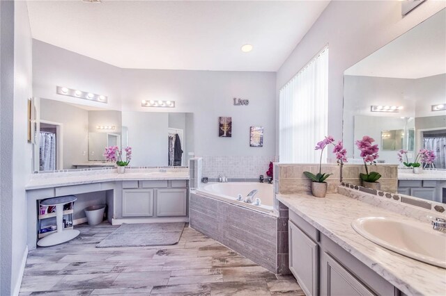 bathroom with vanity, hardwood / wood-style floors, and tiled tub