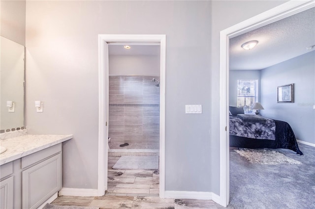 bathroom with vanity, a tile shower, and a textured ceiling