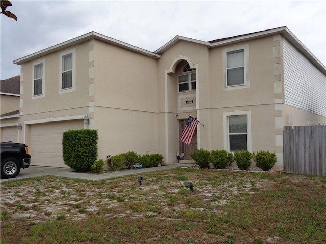 view of front of home with a garage, fence, and stucco siding