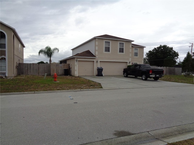 view of front of house featuring a garage, fence, driveway, and stucco siding