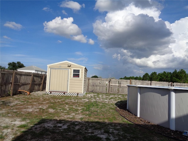 view of yard featuring a fenced in pool, a fenced backyard, an outdoor structure, and a shed