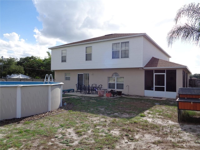 back of property with stucco siding, a lawn, a sunroom, a patio area, and an outdoor pool