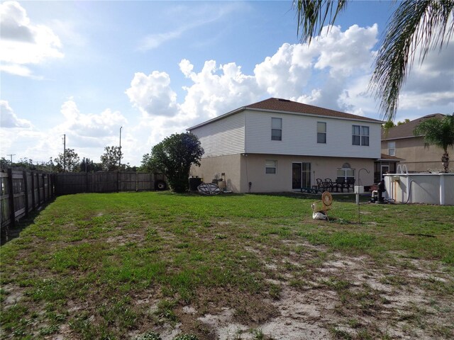 back of house featuring a lawn and a fenced in pool