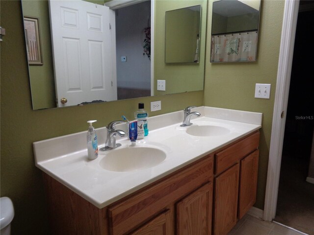 bathroom featuring dual vanity, toilet, and tile patterned floors