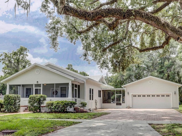 ranch-style home featuring a front yard, a garage, and a sunroom