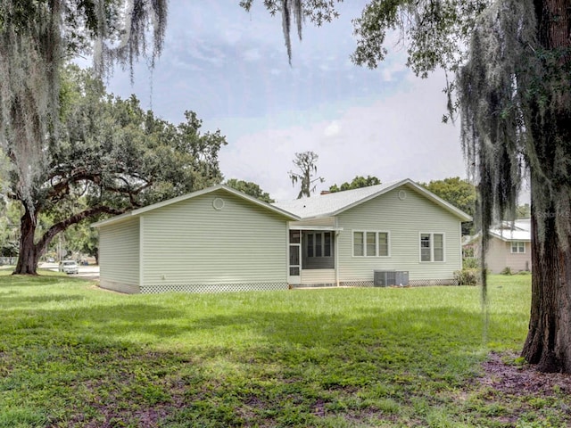 back of property featuring central air condition unit, a lawn, and a sunroom