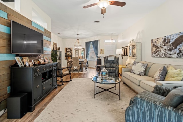 living room with hardwood / wood-style flooring and ceiling fan with notable chandelier