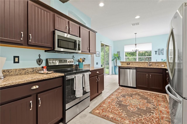 kitchen with dark brown cabinetry, appliances with stainless steel finishes, decorative light fixtures, sink, and light tile patterned floors