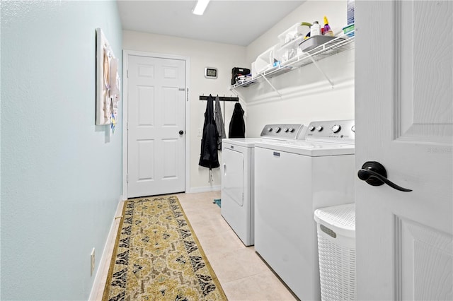 clothes washing area featuring light tile patterned floors and washer and clothes dryer