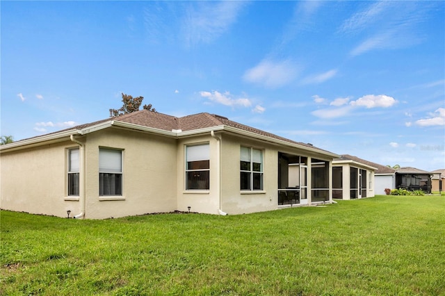 back of property with a yard and a sunroom