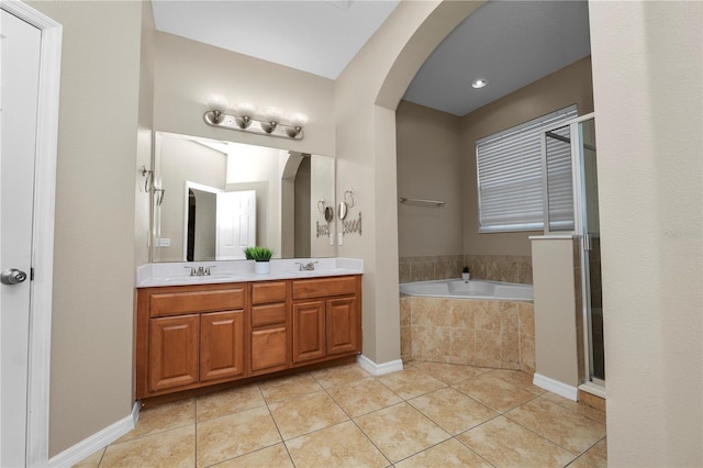 bathroom featuring a relaxing tiled tub, vanity, and tile patterned flooring