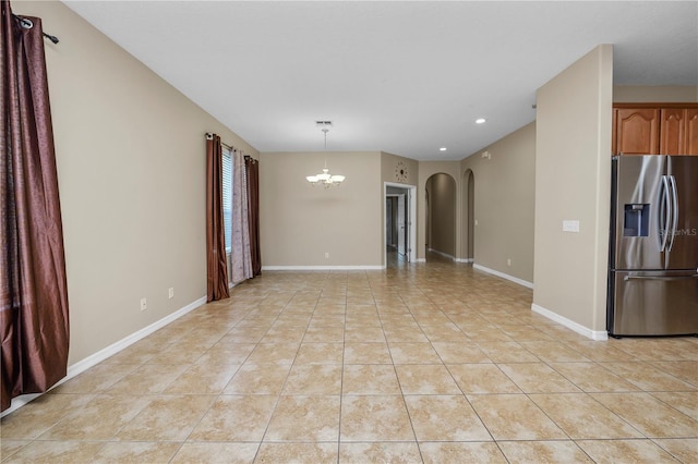 interior space featuring stainless steel refrigerator with ice dispenser, decorative light fixtures, a chandelier, and light tile patterned floors