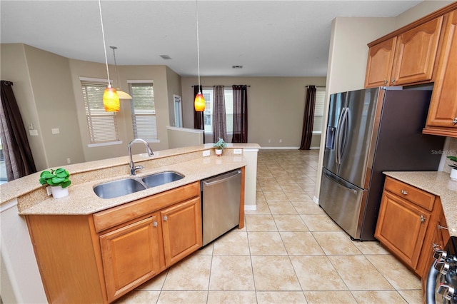 kitchen featuring sink, light tile patterned floors, pendant lighting, stainless steel appliances, and a kitchen island with sink