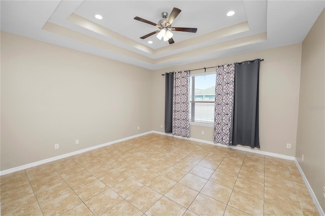 tiled spare room featuring ceiling fan and a tray ceiling