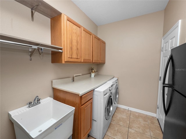 laundry area with cabinets, separate washer and dryer, sink, and light tile patterned floors