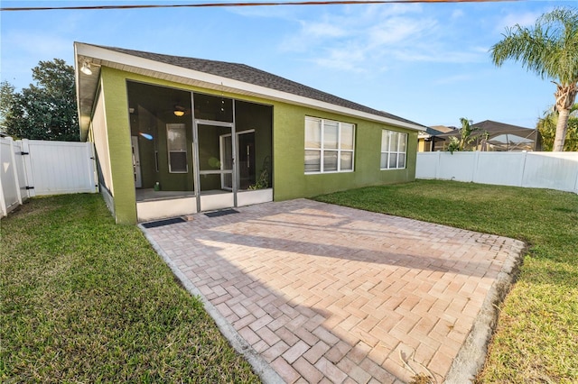 rear view of property with a yard, a patio area, and a sunroom