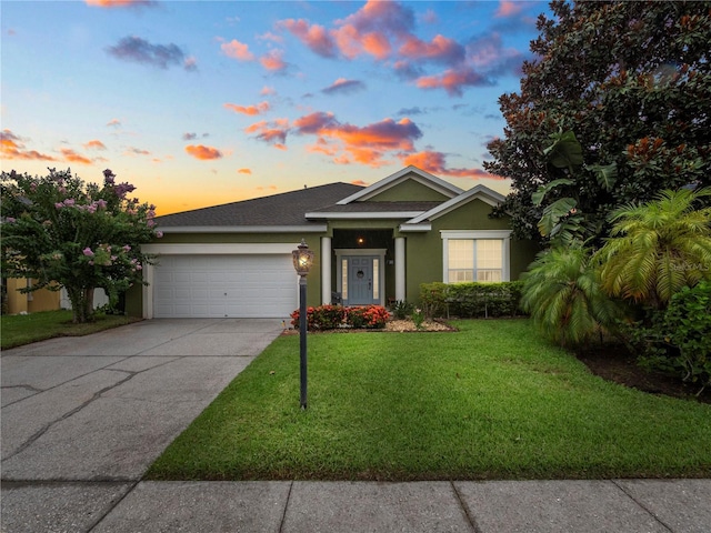 view of front of home with a garage and a lawn