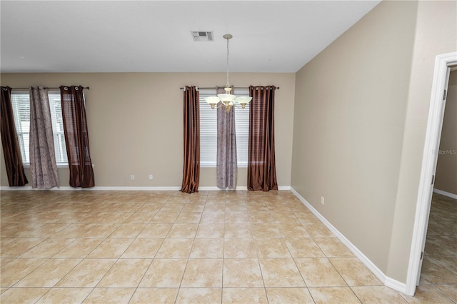 tiled empty room with an inviting chandelier