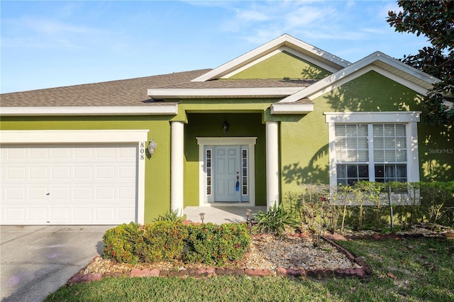 view of front facade with a shingled roof, driveway, an attached garage, and stucco siding