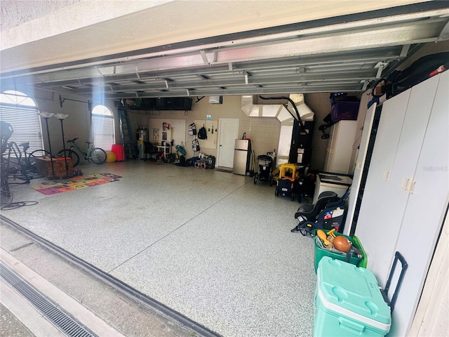 garage with a garage door opener and stainless steel refrigerator